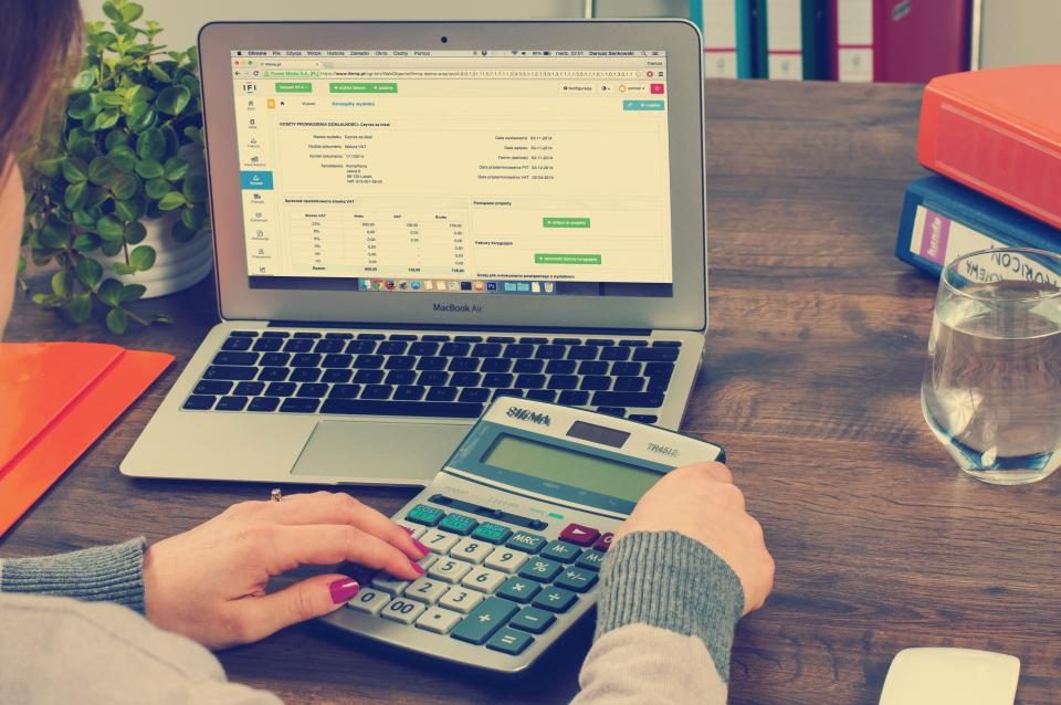Laptop showing a spreadsheet beside a calculator on a desk